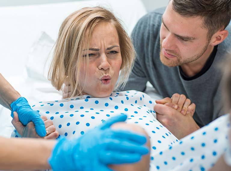 A woman in labor giving birth with her husband